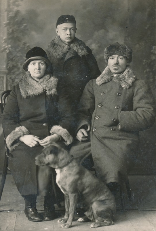 Mustvalge pilt kutsari perekonnast. Pildil kolm inimest kasukatega ja koer.